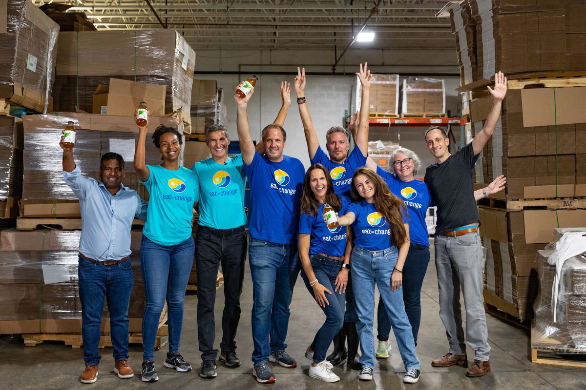 Group of people raising Just Ice Tea bottles in a warehouse