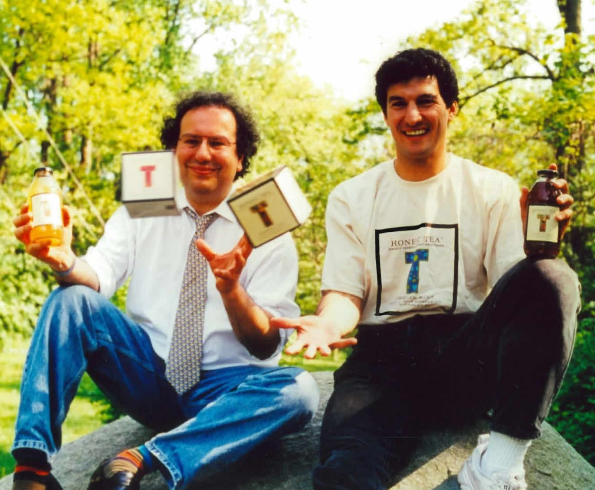 Two Honest Tea founders hold tea bottles and awards outdoors