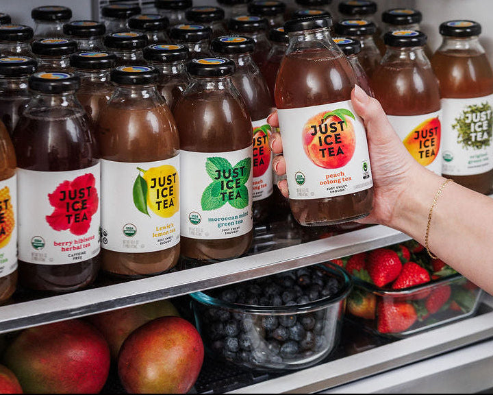 Fridge filled with Just Ice Tea in cans and bottles and other healthy whole foods, fruits and vegetables.